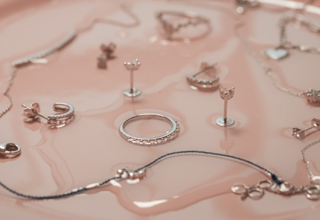 Assorted jewelry pieces displayed on a wet surface, highlighting the importance of proper jewelry care